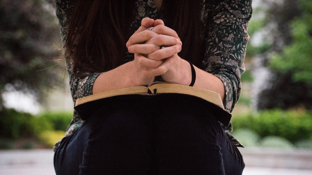 person-sitting-while-reading-book-and-praying