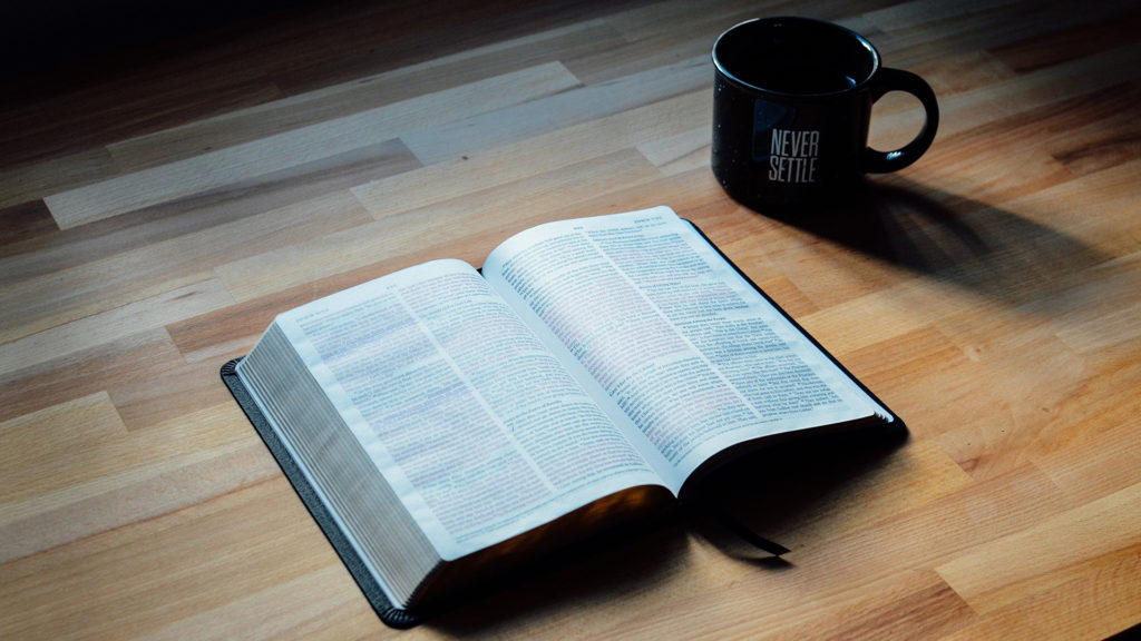 opened-book-beside-black-ceramic-mug