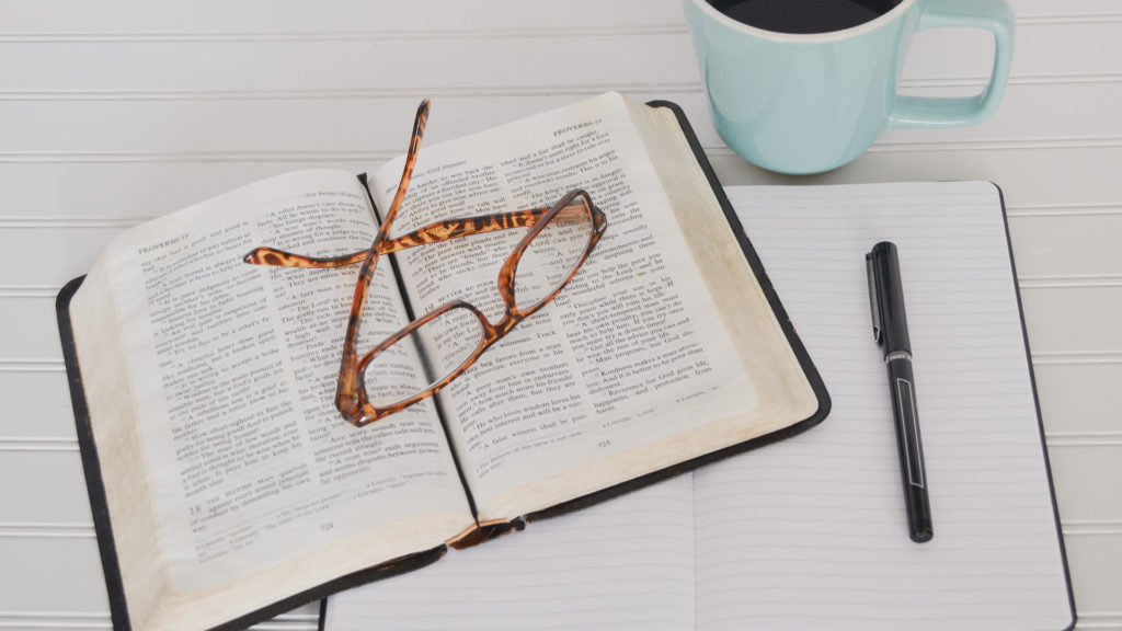 tortoiseshell-eyeglasses-on-top-of-book-near-black-pen-and-teal-mug