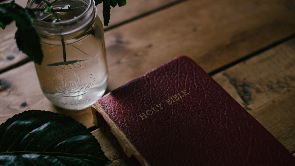Holy-Bible-beside-clear-mason-jar-on-table