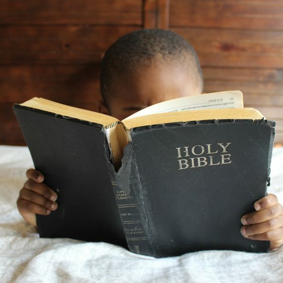 boy-reading-Holy-Bible-while-lying-on-bed