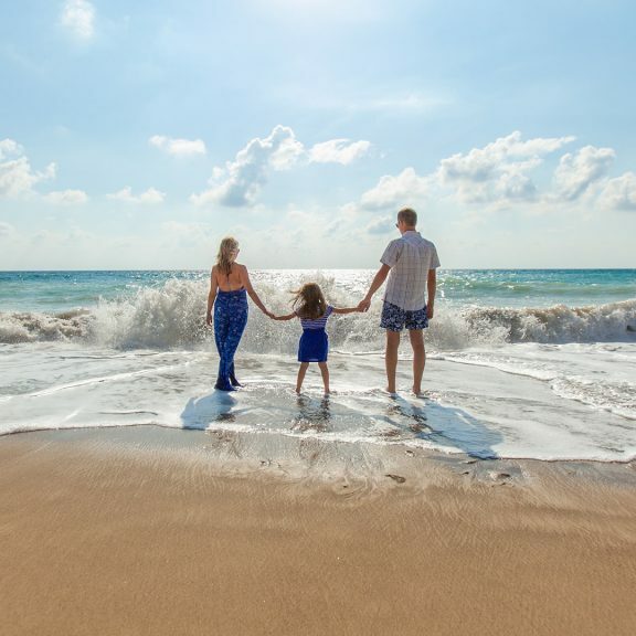 man-woman-and-child-holding-hands-on-seashore