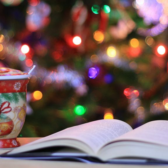 red-and-green-ceramic-mug-beside-book-christmas-tree