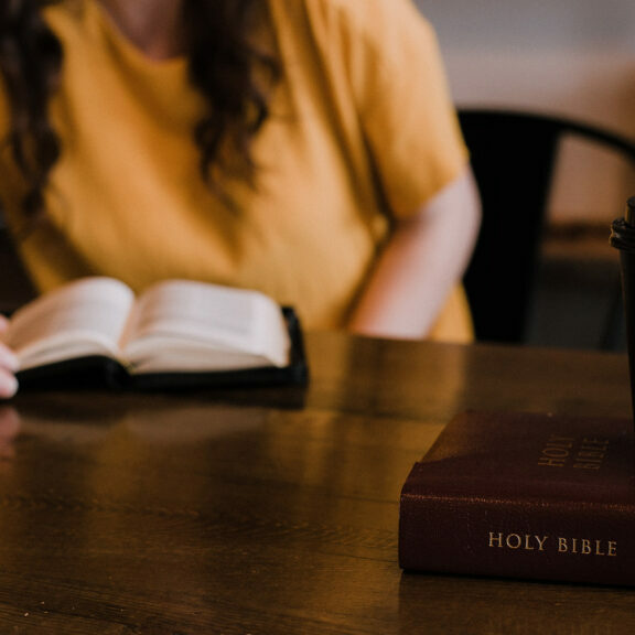woman-sitting-near-bible-and-coffee